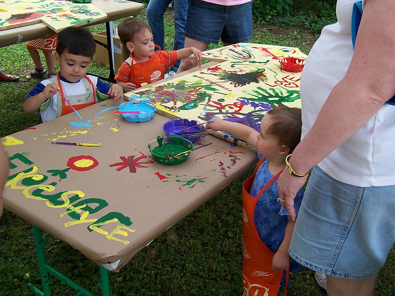 Children painting colorful pictures at an outdoor arts festival